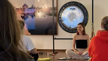 Frau leitet Meditationskurs mit Gong
