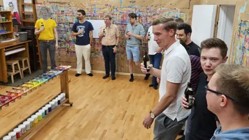 Group of men holding drinks in art studio.