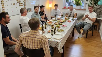 Group sitting at table with food indoors.