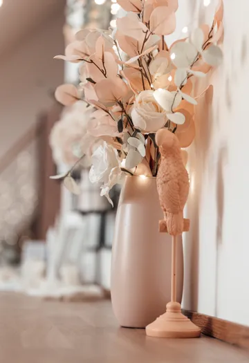 Vase with flowers beside parrot figurine indoors.