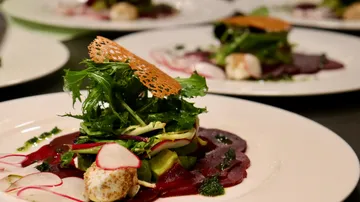 Gourmetsalat auf weißem Teller angerichtet.