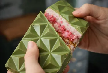 Hands holding green geometric chocolate bar.