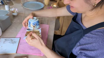 Person repairs ceramic bowl with gold leaf.
