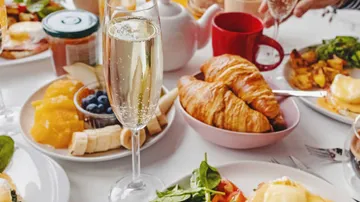 Brunch table with food, champagne, and tea.