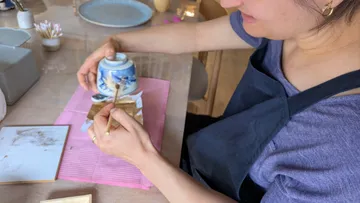 Person repairing blue vase with gold lacquer.