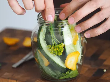 Glas mit frischem Gemüse wird auf einem Tisch gefüllt.