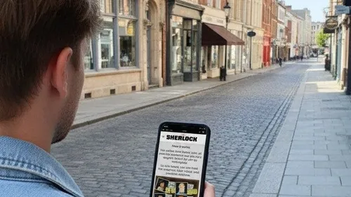 Person hält Handy auf Kopfsteinpflasterstraße.
