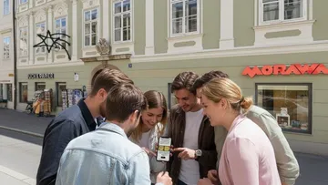 Gruppe schaut auf Handy in Stadtstraße.