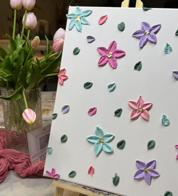 Canvas with colorful flower paintings, tulips beside.
