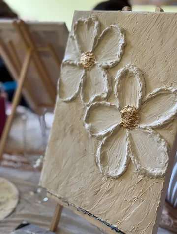 Textured flowers painted on canvas indoors.
