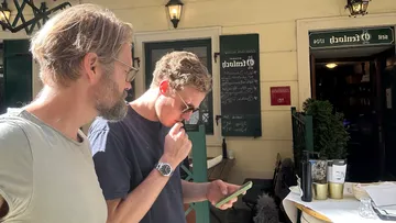 Zwei Männer betrachten Handy in Café.
