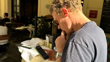 Man checking phone outdoors at a café.