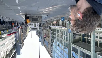 Person with earbuds walks past city buildings.