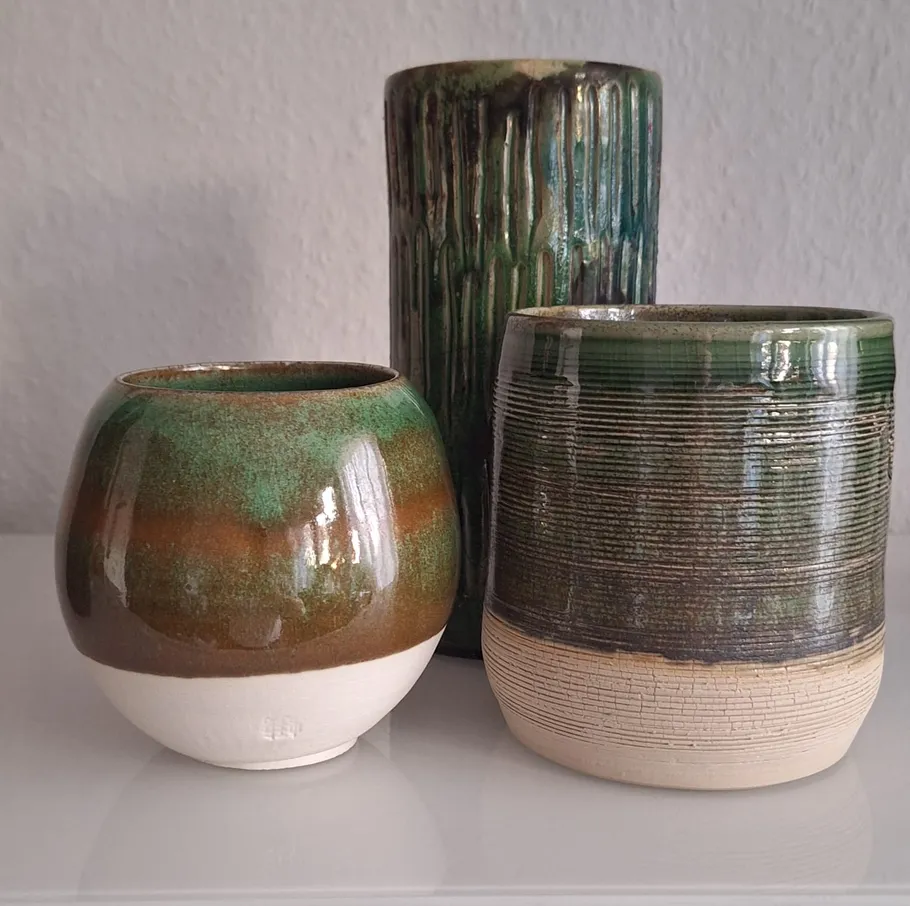 Three ceramic pots on a white surface.