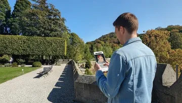 Man using smartphone in scenic garden.