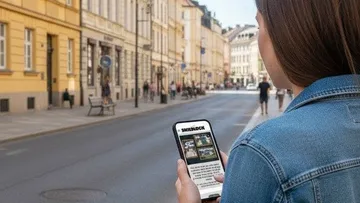 Person liest auf Handy in städtischer Straße.