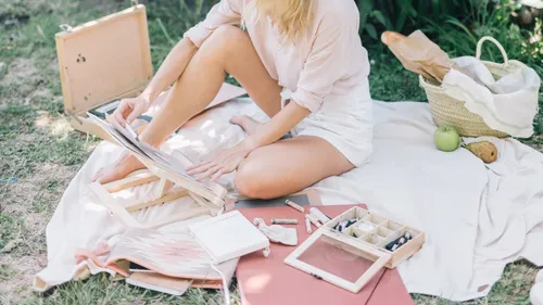 Woman drawing on sketchpad in garden.