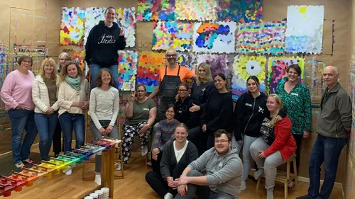Gruppe posiert im Kunststudio mit Gemälden.