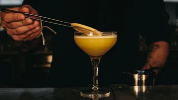 Barkeeper garniert Cocktail mit Zitronenscheibe.
