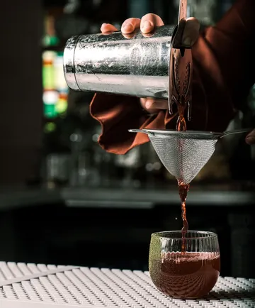 Barkeeper gießt Cocktail durch Sieb
