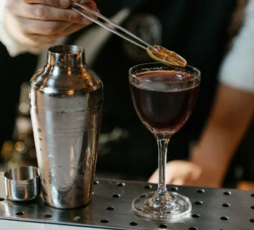 Barkeeper garniert Cocktail mit Zitronenscheibe.