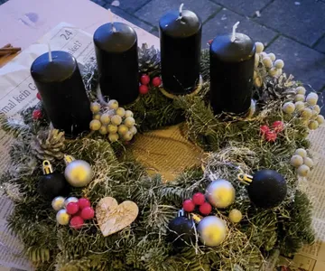 Advent wreath with black candles on newspaper.