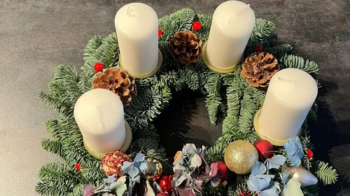 Advent wreath with four unlit candles on table.