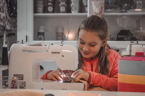 Girl sewing with a machine indoors
