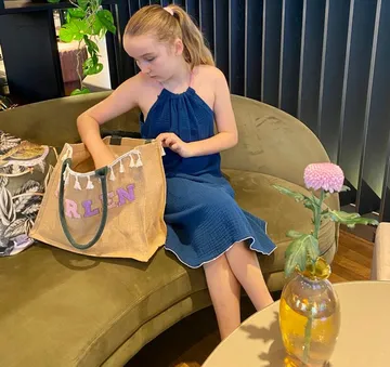 Mädchen durchsucht Tasche auf einem Sofa.