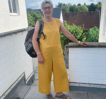 Lächelnde Frau im gelben Outfit draußen.