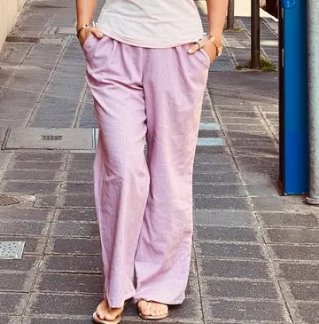 Person stands wearing pink pants, outdoor sidewalk.
