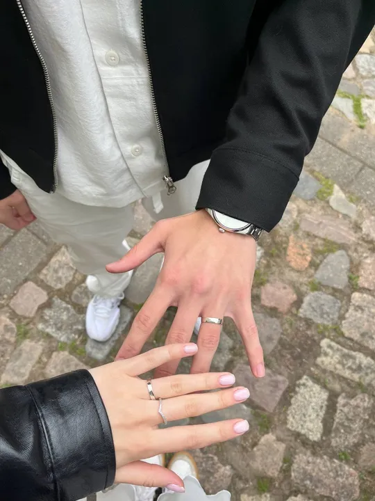 Hände mit Ringen berühren sich auf Kopfsteinpflaster.