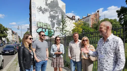 Group of tourists listens to a guide outdoors.