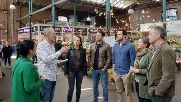 Group conversing in a bustling indoor market.