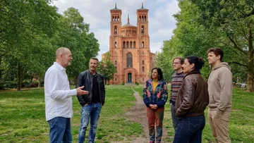 Group talking in park near red brick building.