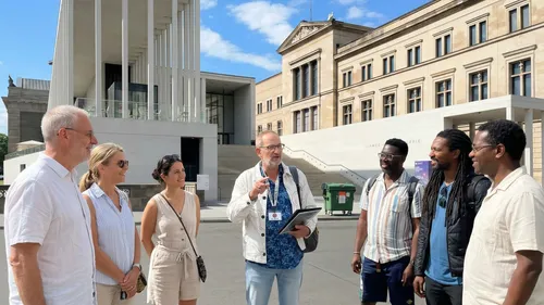 Group of people listening to a guide outside museum.