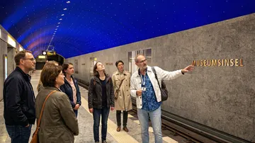Führer erklärt Gruppe in U-Bahn-Station.