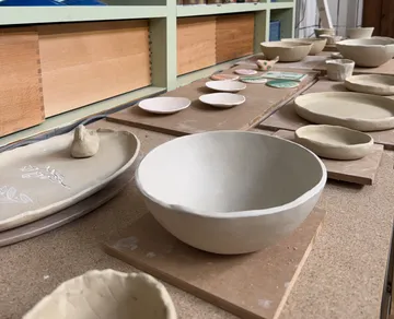 Unglasierte Ton-Schalen auf Holzregalen.