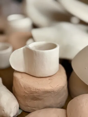 Ceramic cup on clay mound, blurred background.
