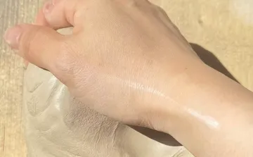 Hand drückt Ton auf Holztisch.