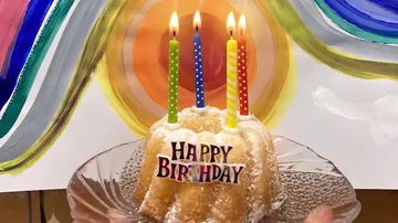 Kleiner Kuchen mit Kerzen, bunter Hintergrund.