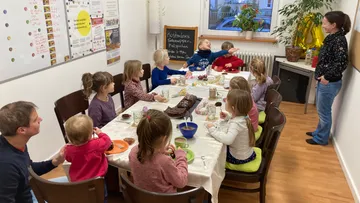Kinder sitzen am Tisch und essen Snacks.
