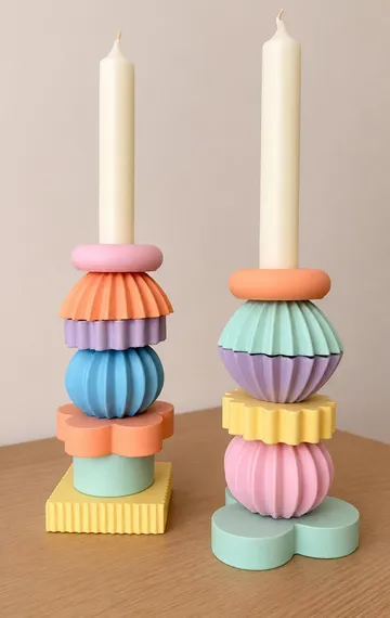 Zwei bunte Kerzenhalter auf Holztisch.