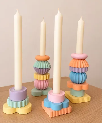 Bunte Kerzen auf geometrischen Haltern, Holztisch.