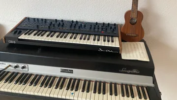 Synthesizer and keyboard on a piano with sheet music.