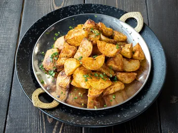 Roasted potatoes garnished with herbs on plate.