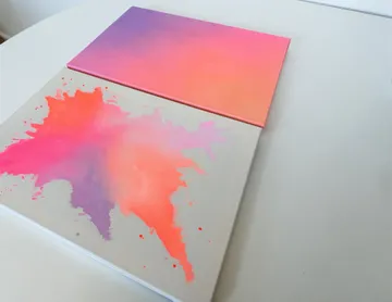 Zwei bunte Leinwände auf einem weißen Tisch.