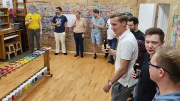 Gruppe von Menschen mit Getränken im Atelier.