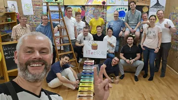 Gruppe posiert im Kunstatelier mit Gemälden.