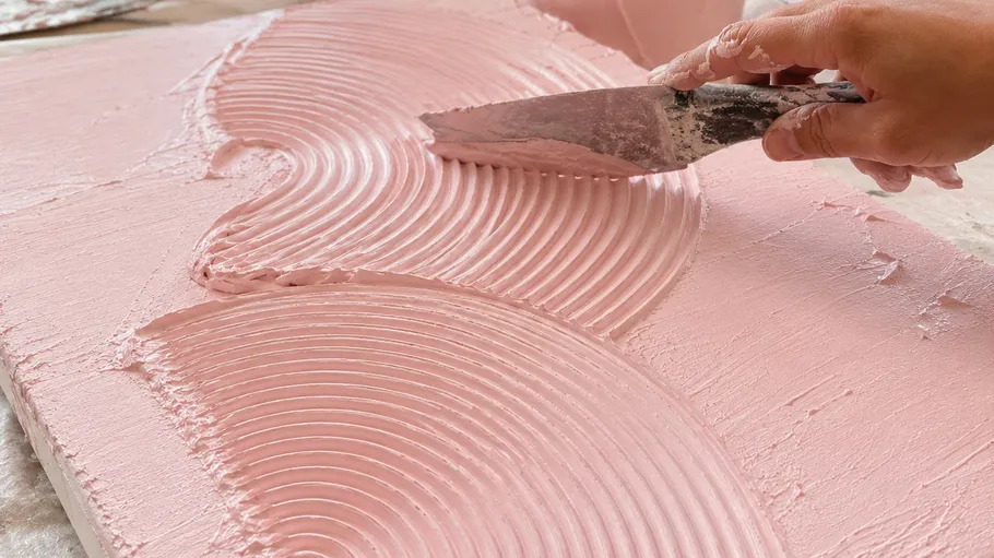 Hand glättet rosa Putz mit Spachtel.